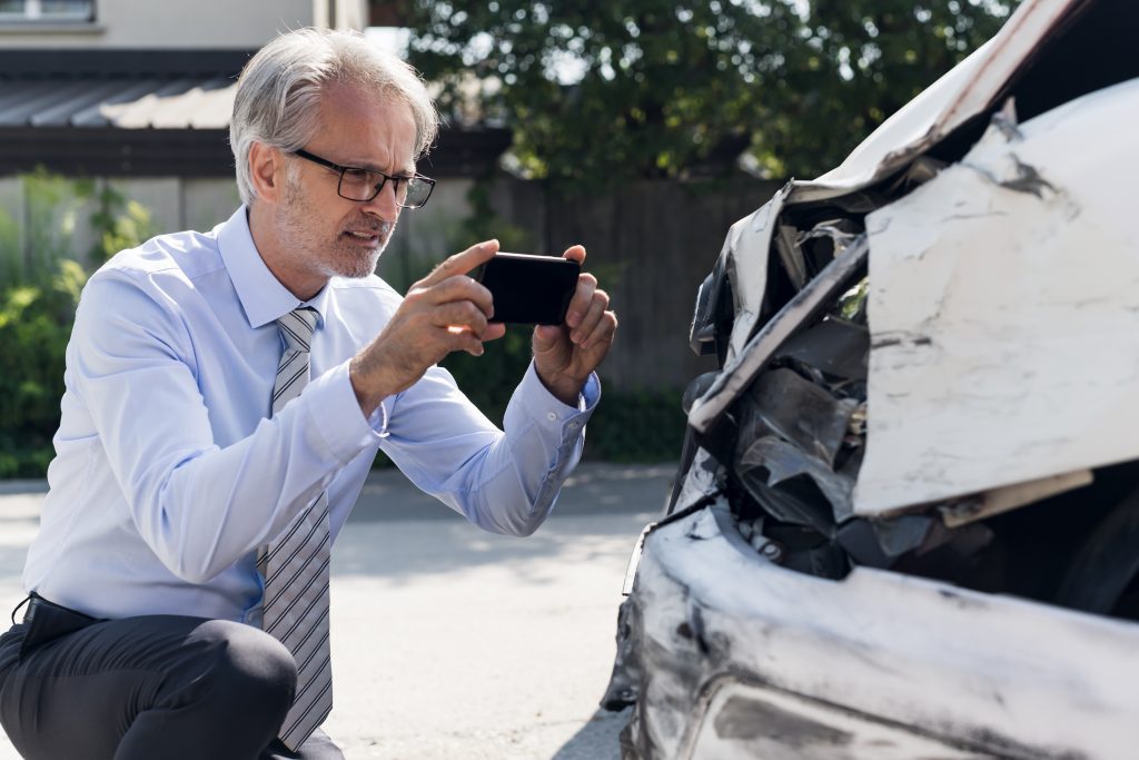 Car Insurance Adjuster Examining Vehicle Damaged in Accident