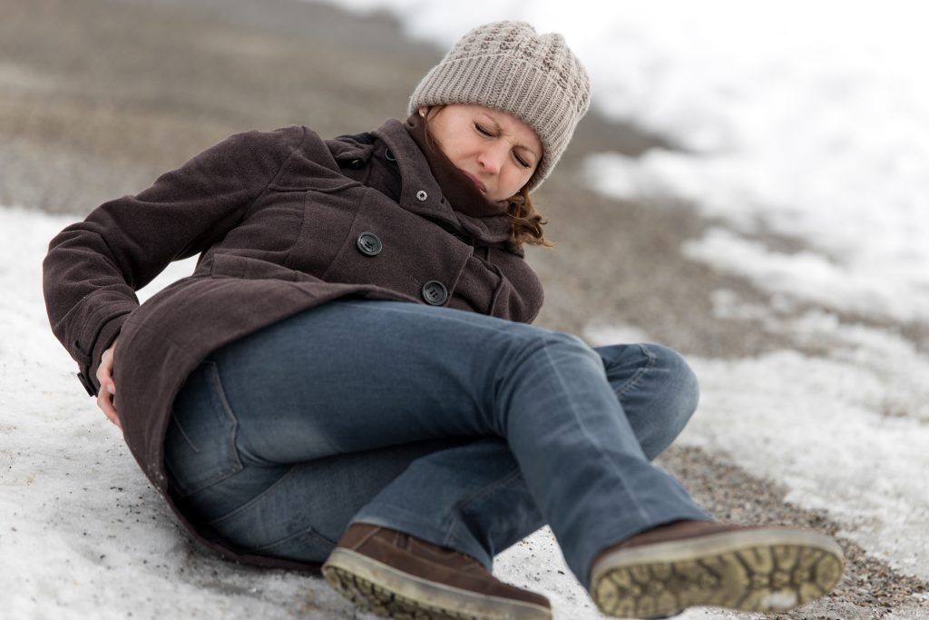 young woman on ground after slipping and falling on ice because of a negligent store owner